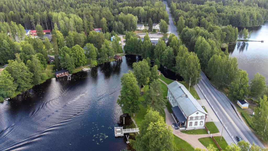 Ilmakuva Mäntyharjun kirkonkylältä. Oikeassa kulmassa näkyy Taidekeskus Salmela ja sen edustalla menevä Vihreän kullan kulttuuritie, mikä jatkaa matkaa kuvan halki. Kuvan vasemmalla puolella vesistöä ja metsää. 