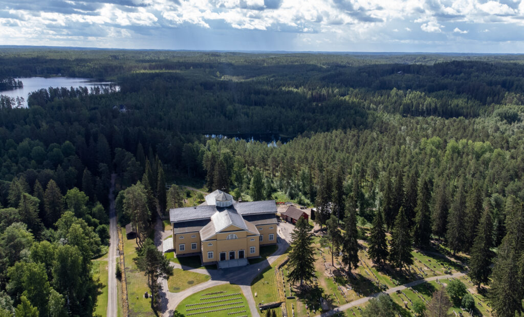 Ilmakuva Mäntyharjun kirkonkylältä. Edustalla Mäntyharjun kirkko, minkä takaa alkaa silmien kantamattomiin jatkuva metsä. 