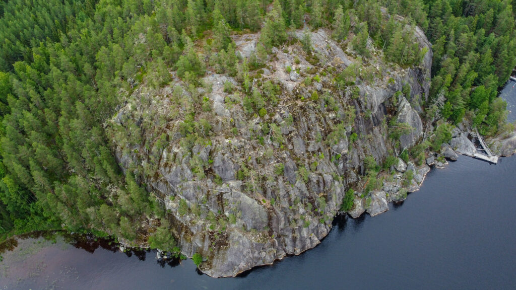 Ilmakuva Pisamalahden linnavuoresta. Linnavuori on kivinen kallio, missä kasvaa harvakseltaan puito. Kallion ympäröi takaa metsä ja edustalla vesistö.