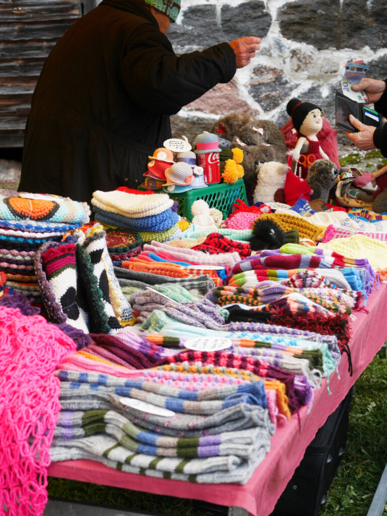Tapahtuman markkina-alueen myyjäpöytä, missä on myynnissä paikallisen myyjän tekemisä käsitöitä kuten sukkia ja patalappuja. 